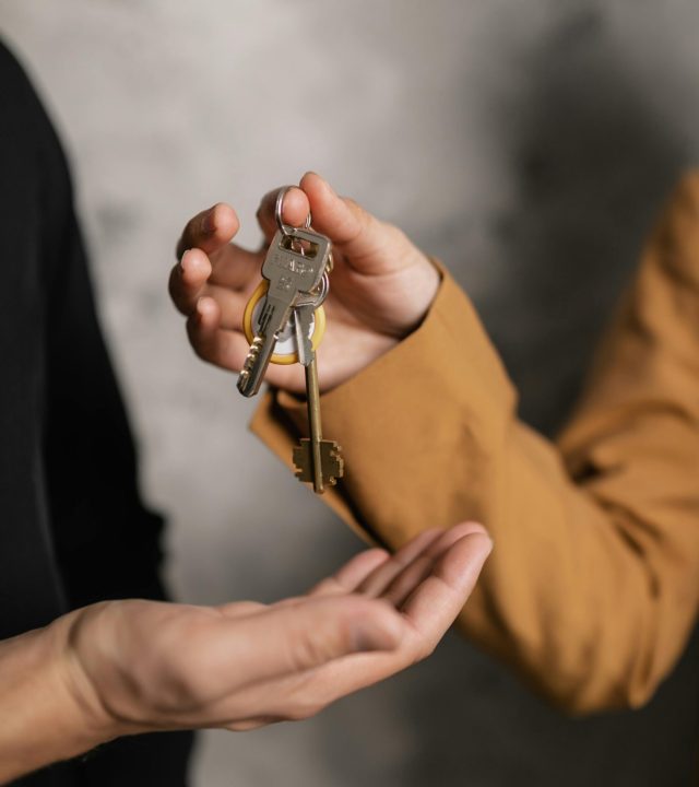 Two adults exchanging house keys, symbolic of property transfer or rental agreement.